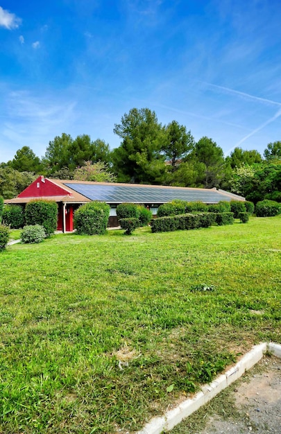 A house with solar panels on the roof and a lush green garden, representing sustainability and energy efficiency.