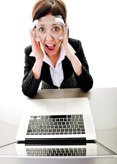 A person looking at a computer screen with a surprised expression while holding a magnifying glass and looking at a credit report.